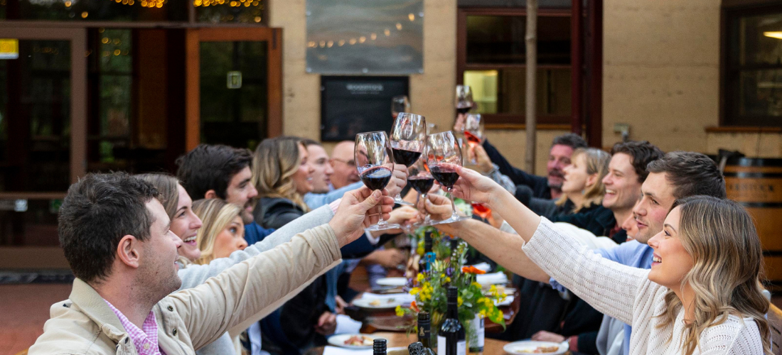 Long table of people raising their wine glasses to toast 